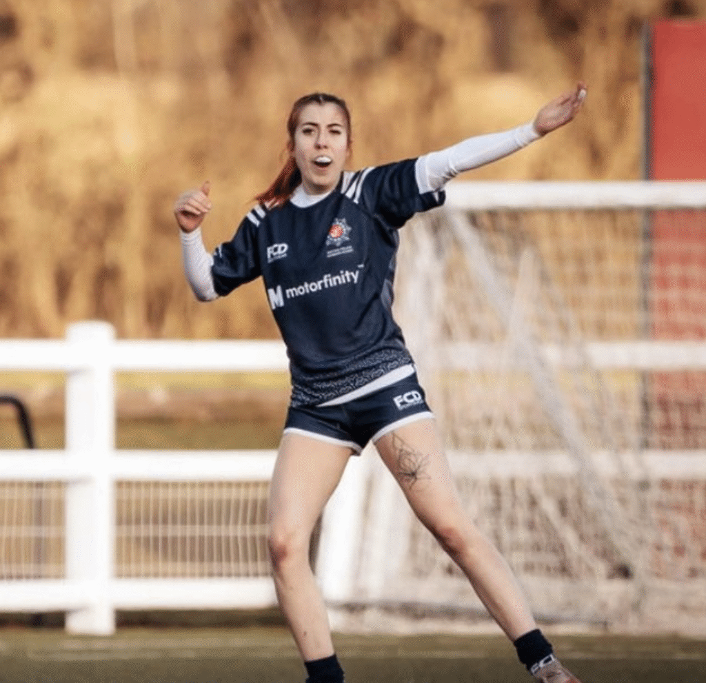 A woman in blue rugby kit shouts out instructions during a game of rugby