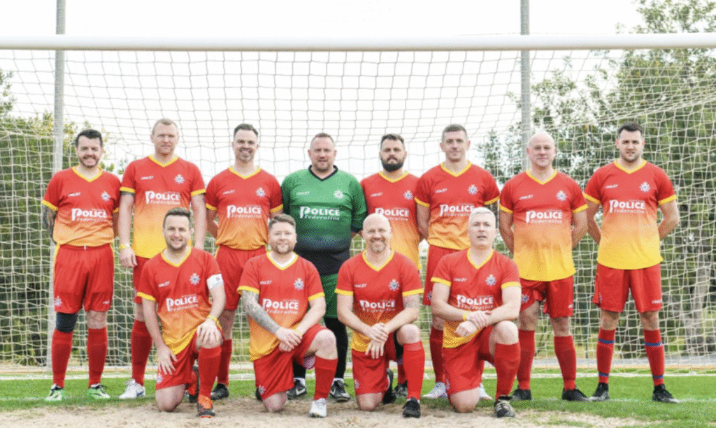 A team of footballers pose on two rows in the red and yellow kit