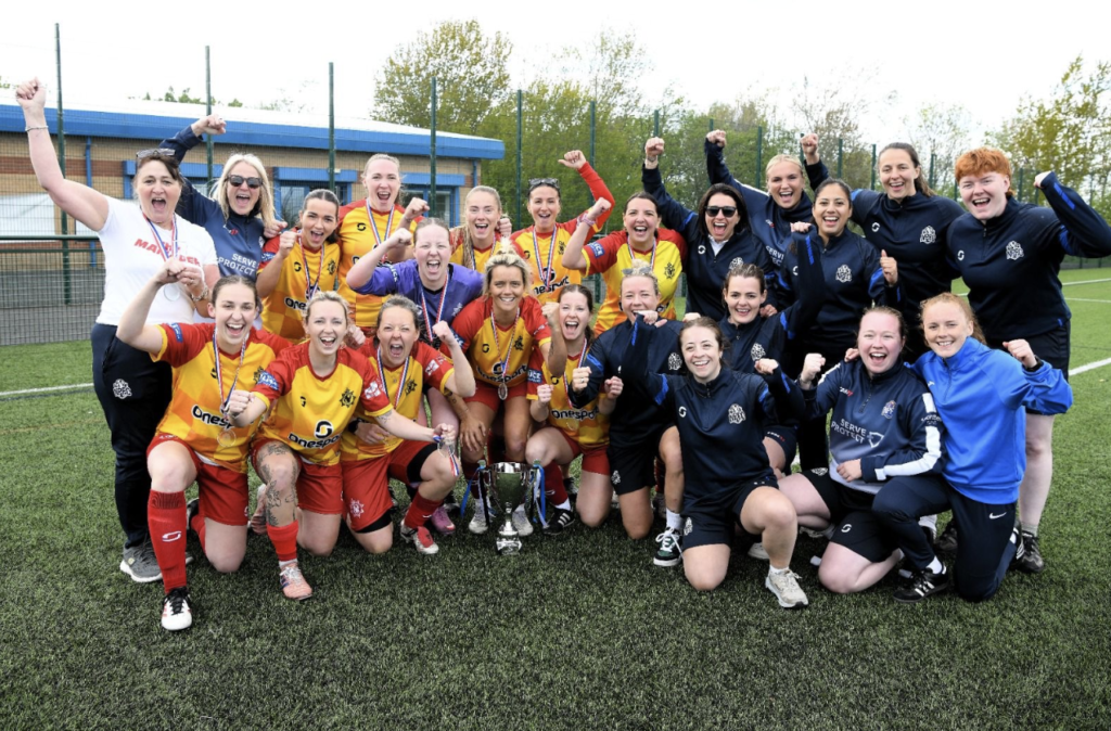 A team of women footballers dressed in yellow and blue kits celebrate after winning the PSUK title